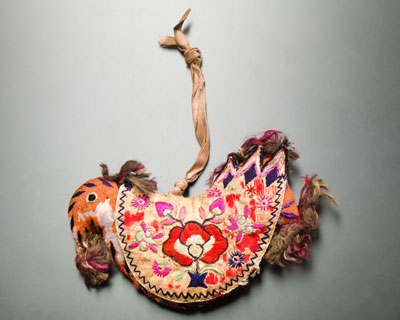 긴 끈이 달린 끝에 호랑이 형태 인형이 붉은 꽃이 수놓인 옷을 입고 있는 사진